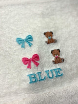 Embroidery design options on a white towel: blue bow, pink bow, blue bear and pink bear, with a name sample in blue thread