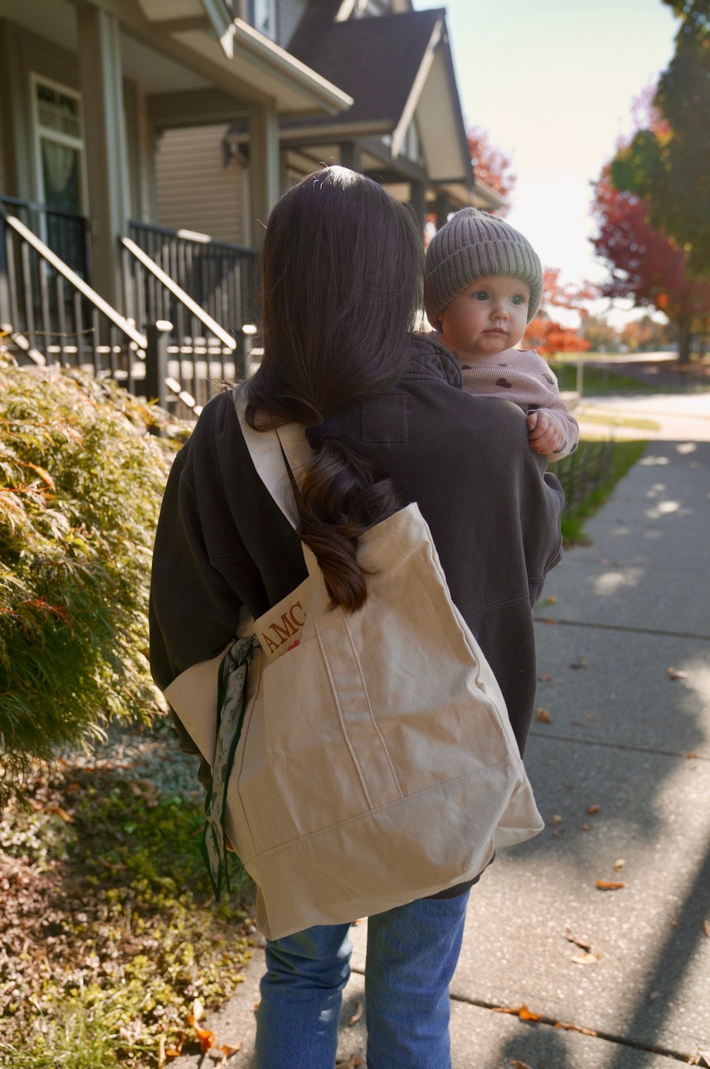 Custom embroidered natural tote with AMC initials carried over the shoulder